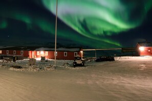 A building with a red exterior, a snow-covered ground, and a visible light pole. - Old Camp (Kangerlussuaq)