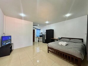 Habitación de hotel con cama, televisión, escritorio y kitchenette.