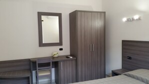 Ein Schlafzimmer mit einem Bett, einem Kleiderschrank, einem Schreibtisch mit Stuhl und einem Spiegel.