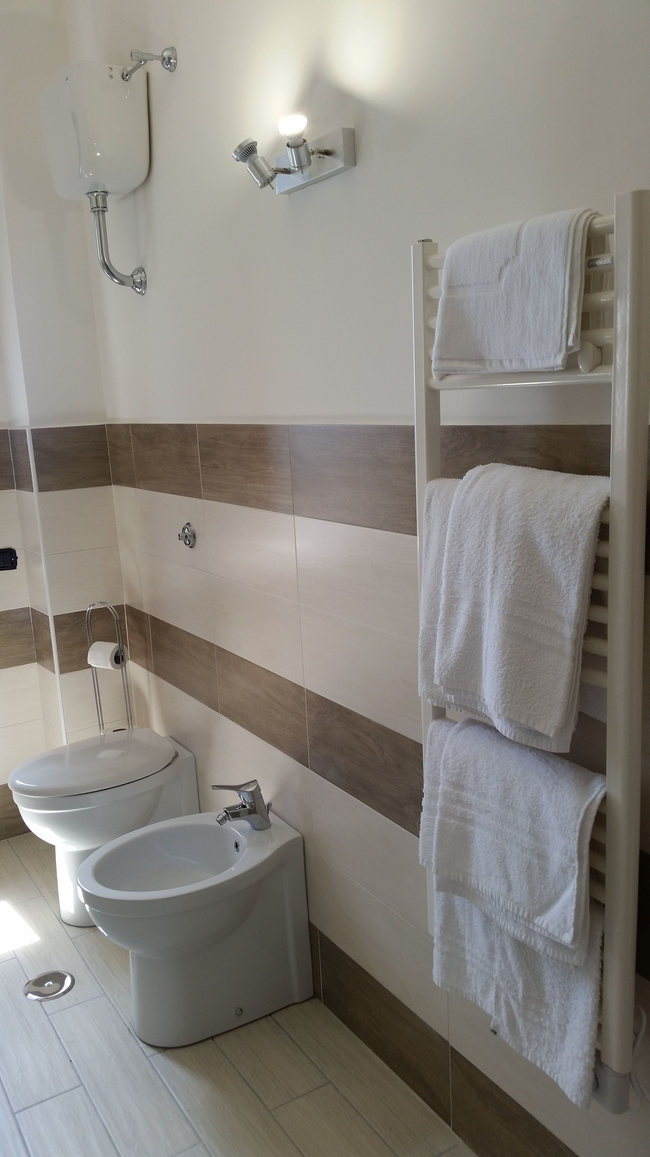 Un bagno con bidet, WC, lavandino e porta asciugamani.