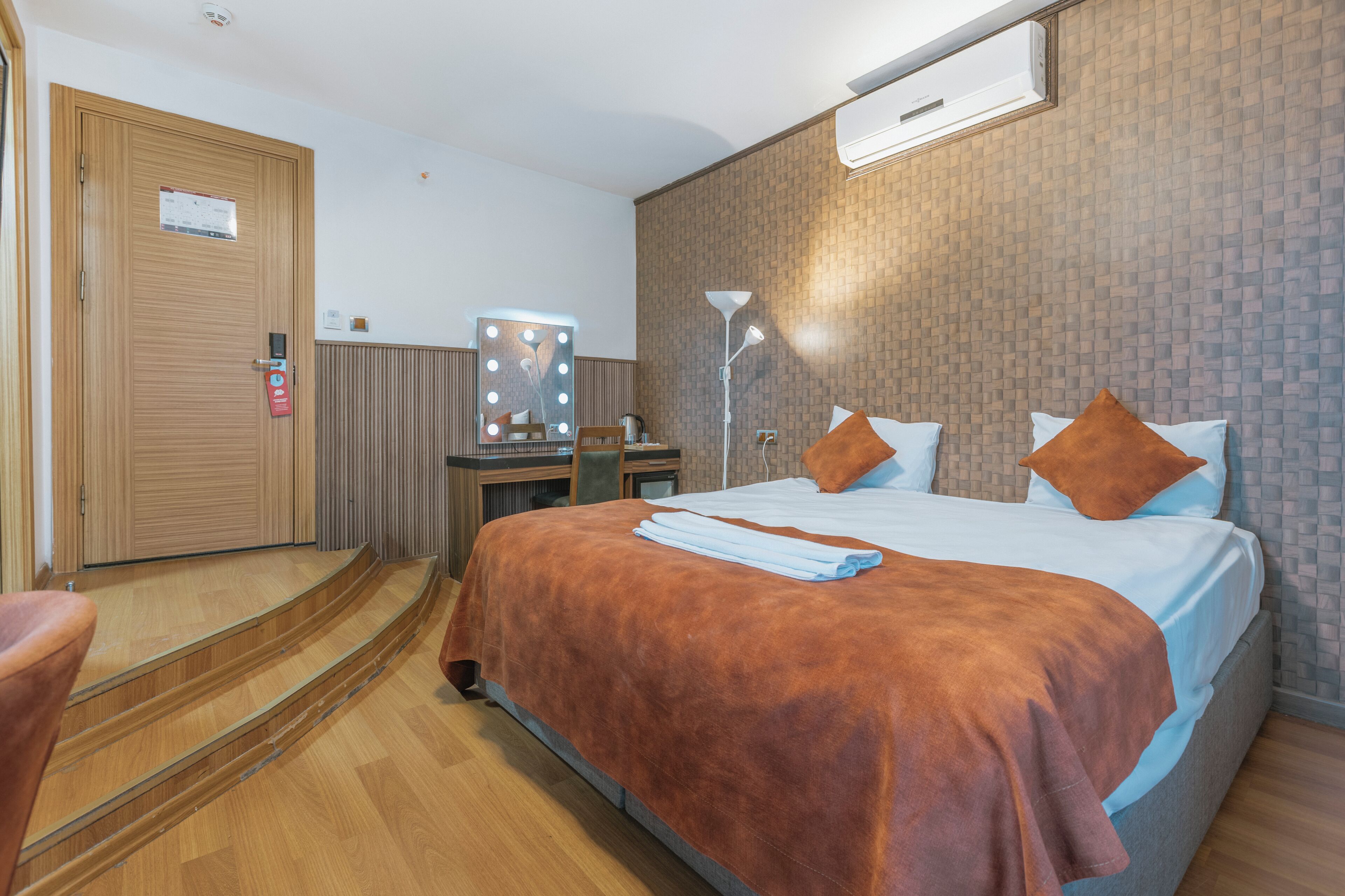 Una habitación de hotel con una cama, un escritorio con espejo, una silla y una escalera.