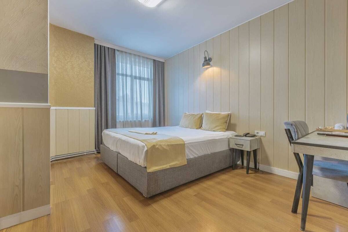 A bedroom with a bed, bedside table, and a desk with a chair.