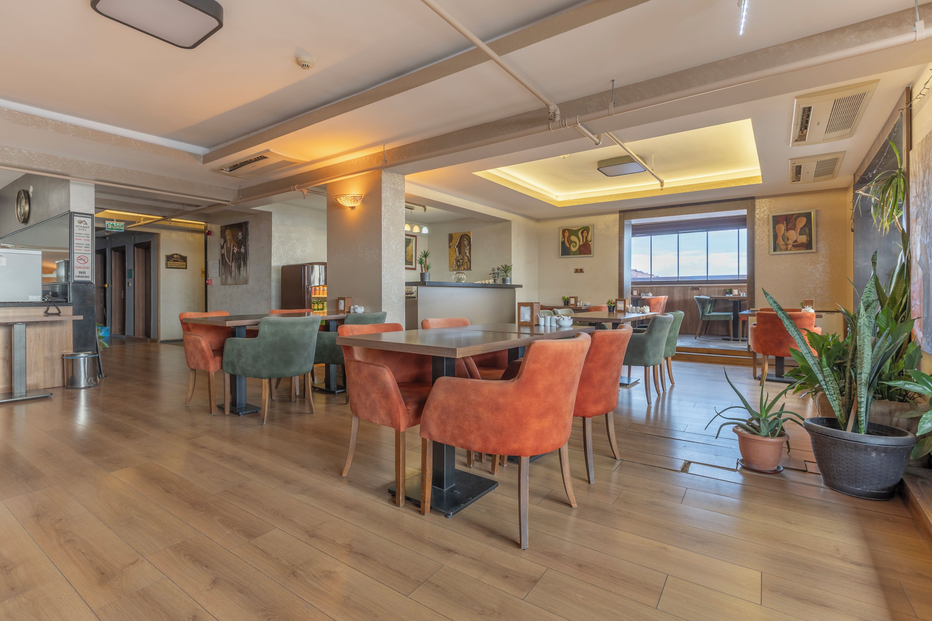 A spacious dining area with wooden flooring, orange chairs, and a central table.