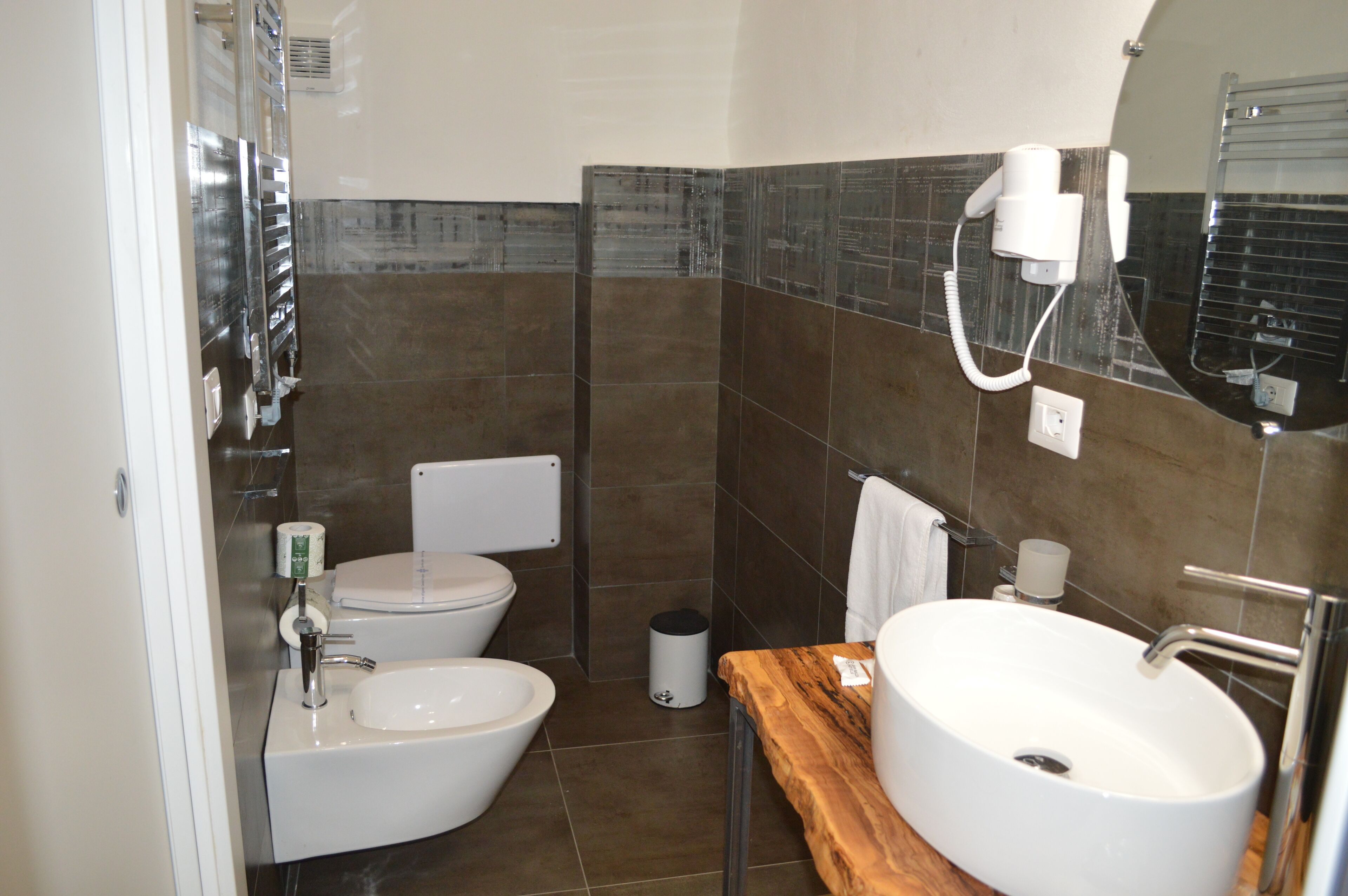 A modern bathroom with a toilet, bidet, sink, and a mirror.