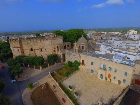 A historic stone building with a courtyard, surrounded by modern buildings and a clear view of the cityscape.