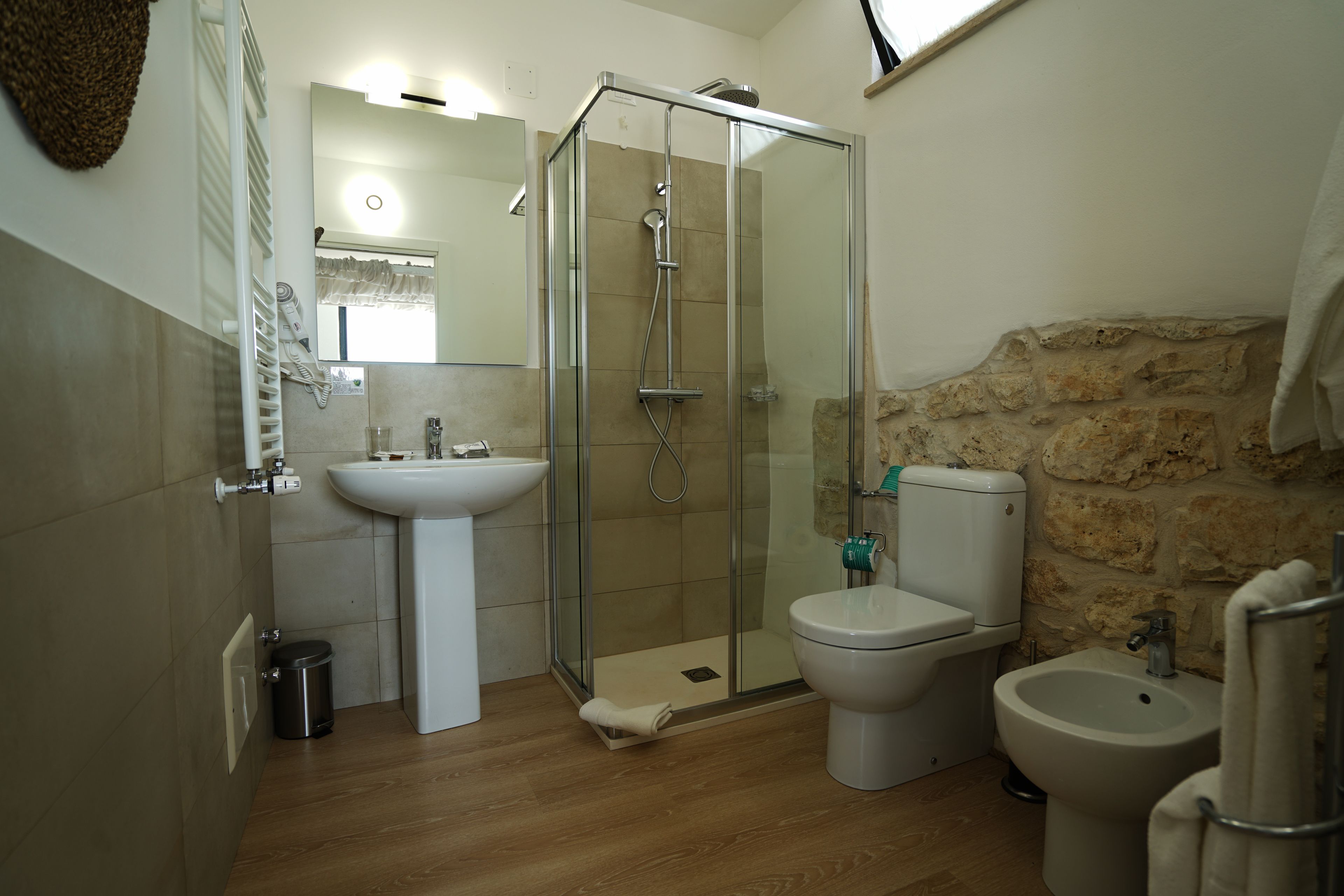 Un baño con ducha de vidrio, lavamanos, inodoro y bidé.