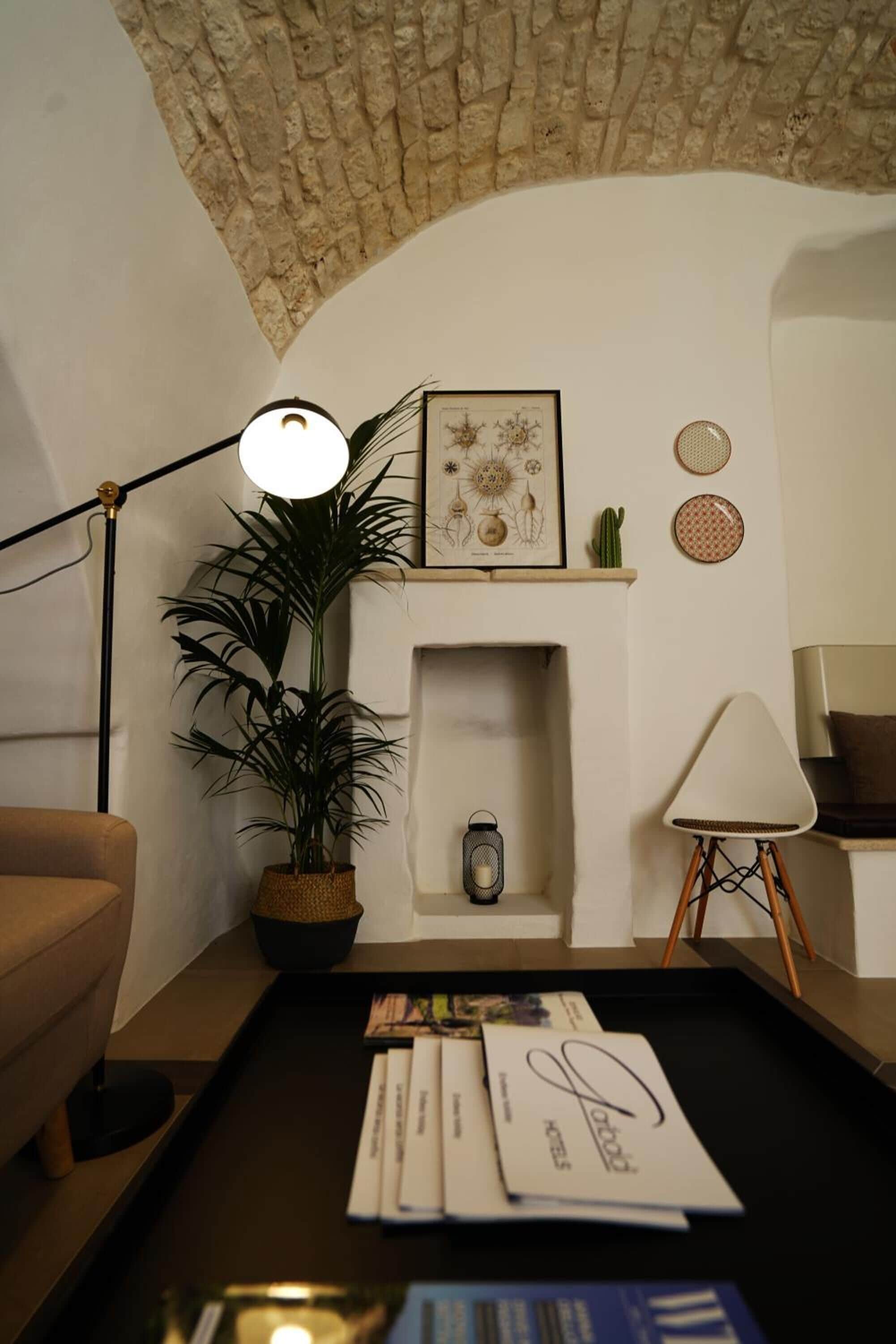 Una sala de estar acogedora con chimenea, una planta en maceta, una lámpara y una mesa de centro con revistas.