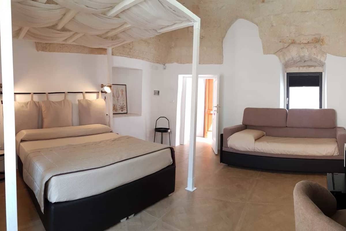 Une chambre à coucher avec un lit, un canapé, un bureau et une chaise.