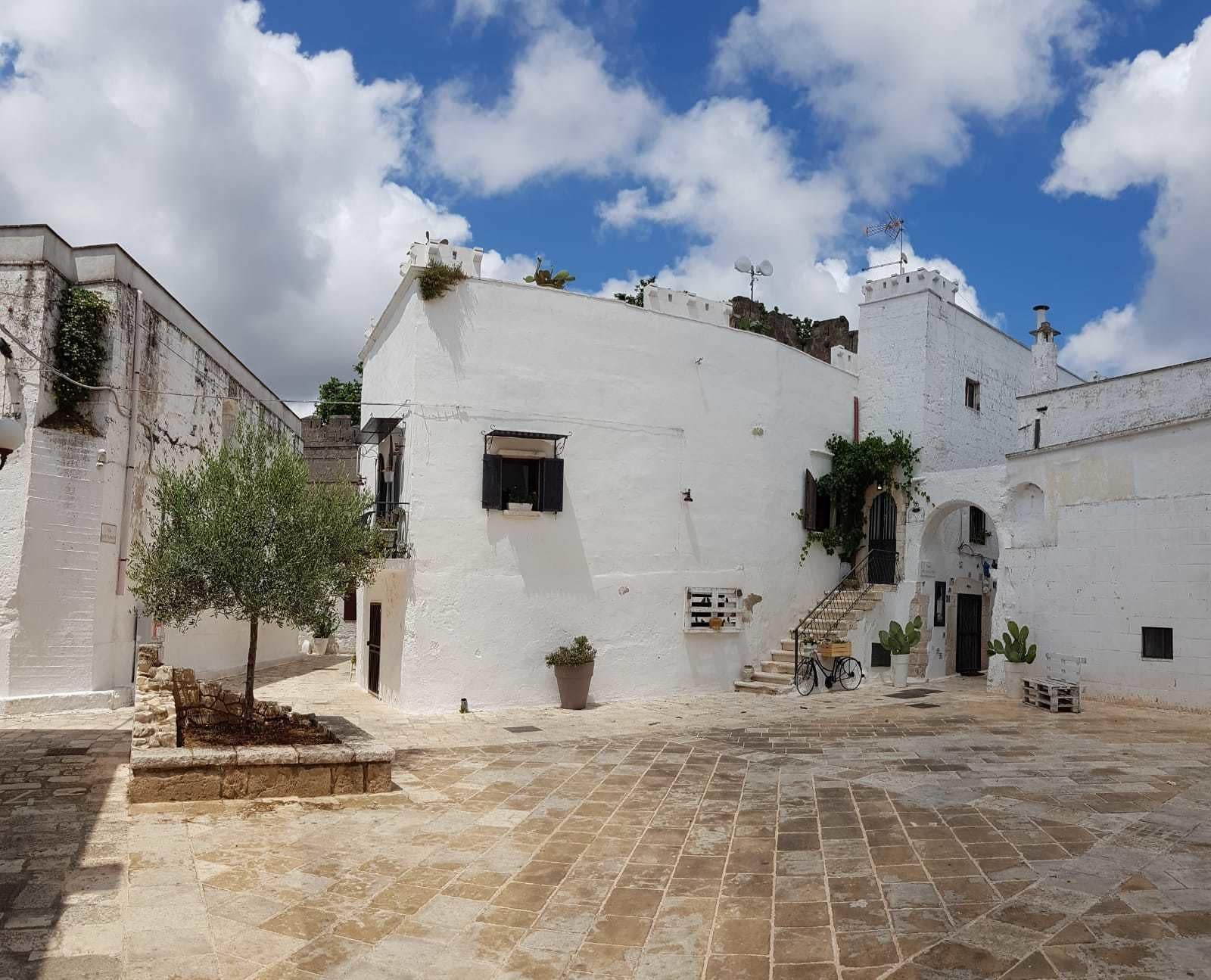 Un patio con edificios blancos, un árbol y una bicicleta.