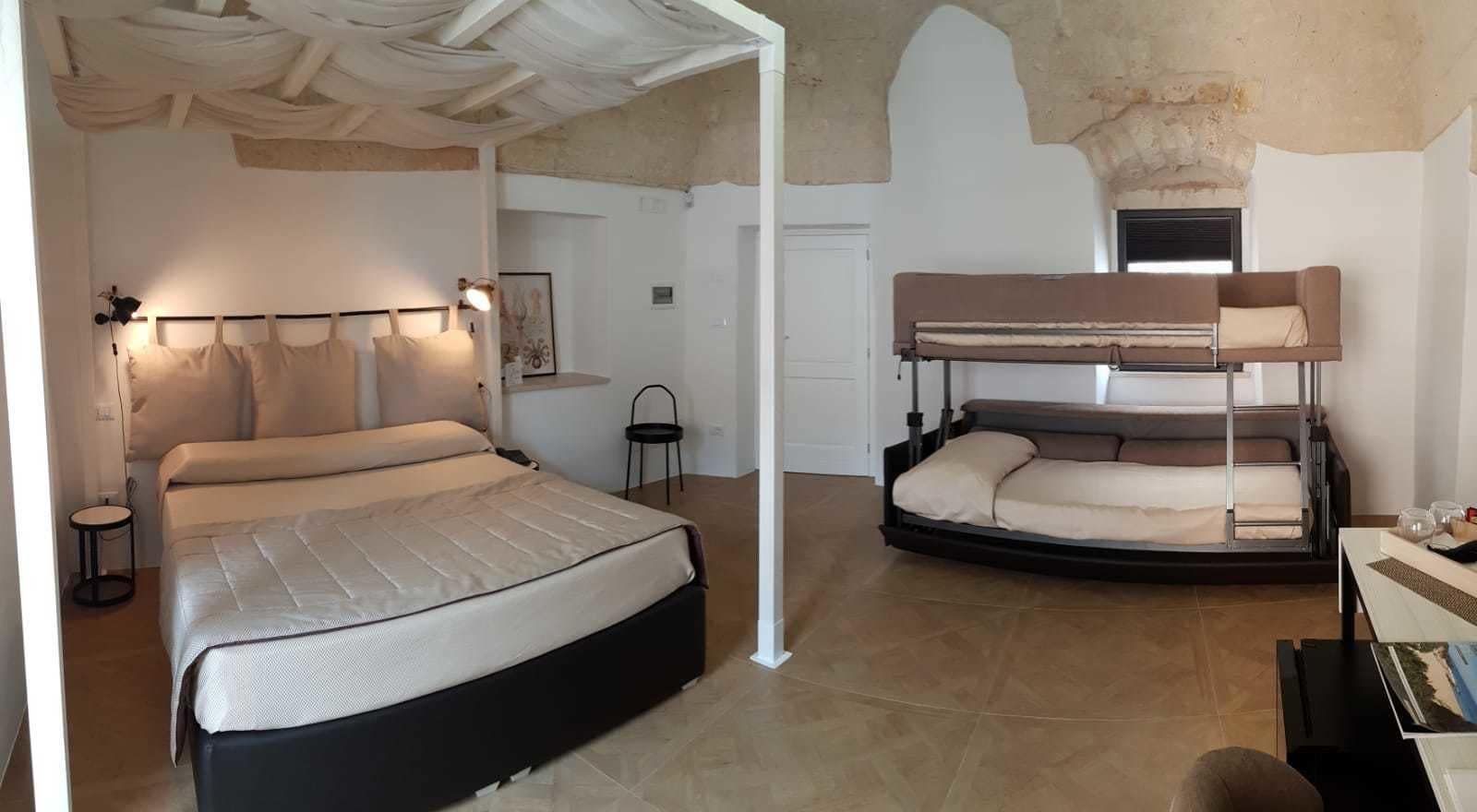 Un dormitorio con una cama, una litera, una mesita pequeña y una silla.