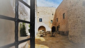 An outdoor courtyard with stone walls, a central archway, and outdoor seating. - Dimora Sant'Anna (Carovigno)