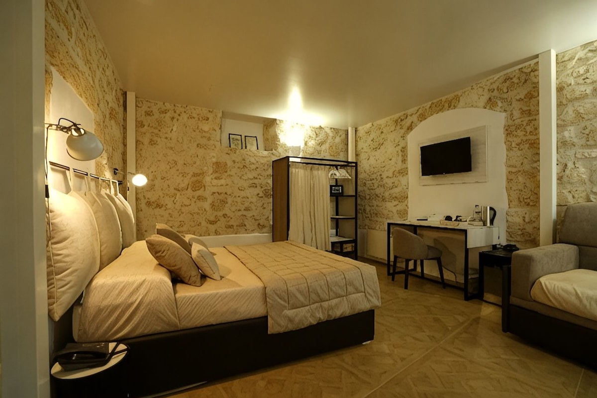 Une chambre à coucher avec un lit, un bureau, une chaise et un téléviseur fixé au mur.