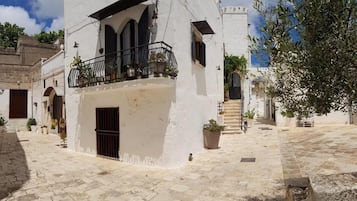 Un edificio blanco con un balcón, una puerta y una escalera que lleva a una torre.