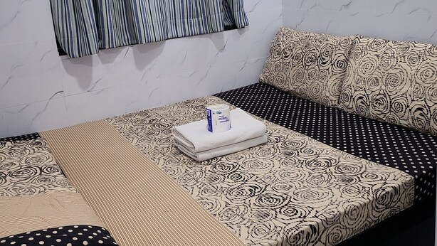 Une chambre à coucher bien rangée, avec un lit, des oreillers et une fenêtre avec des rideaux.