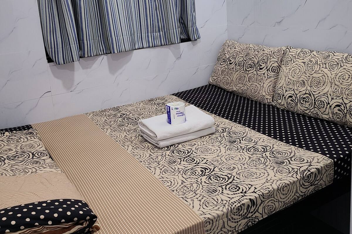 Une chambre à coucher bien rangée, avec un lit, des oreillers et une fenêtre avec des rideaux.
