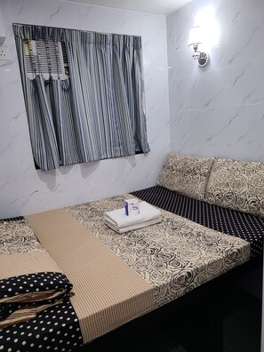 Ein ordentlich eingerichtetes Schlafzimmer mit Bett, Kissen und einem Fenster mit Vorhängen.