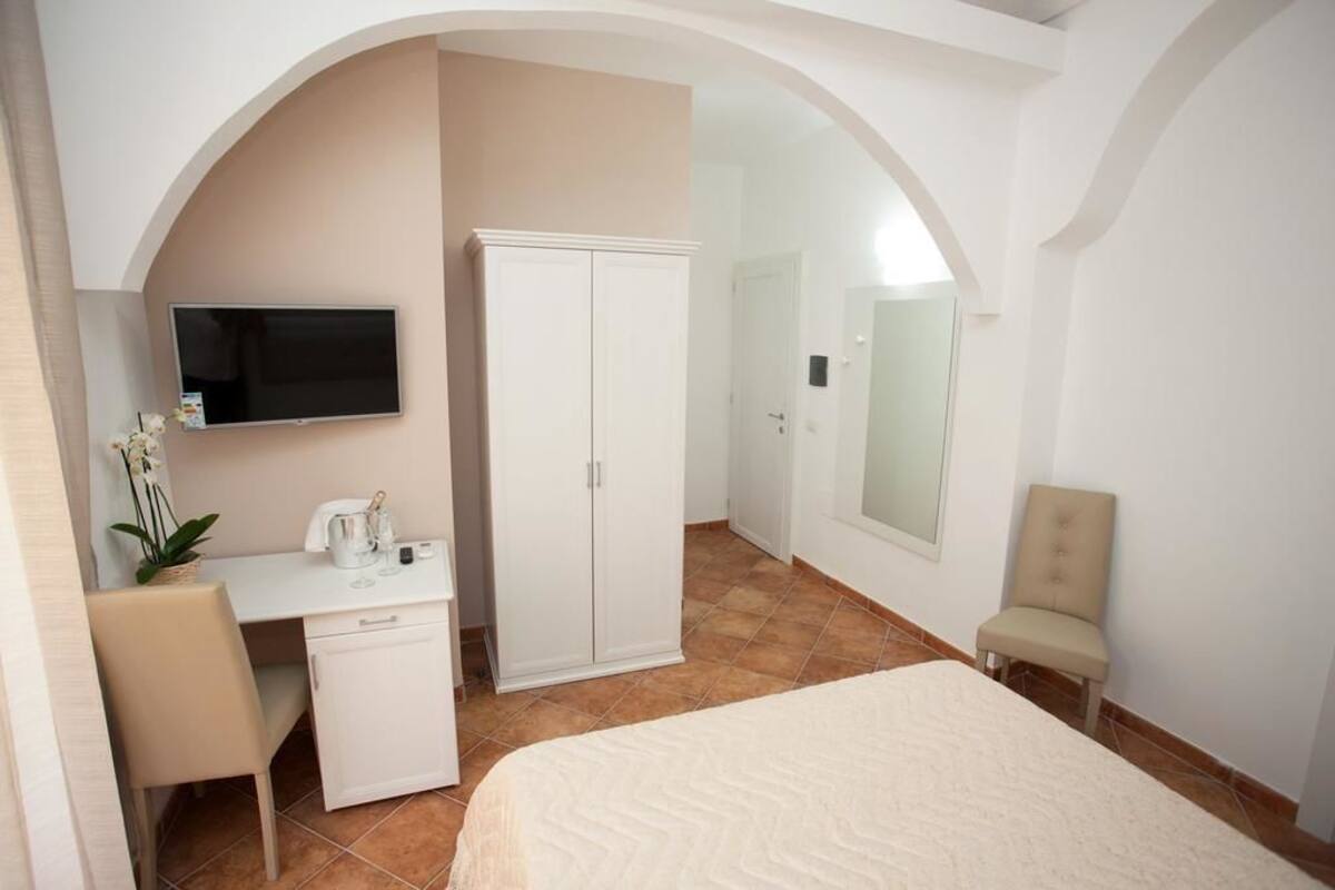 A bedroom with a bed, a desk, a wardrobe, a television, and a chair.