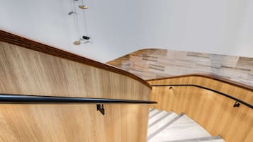 A wooden staircase with a black handrail and a herringbone-patterned floor.