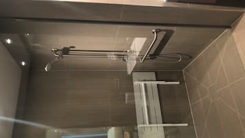 A modern bathroom with a glass shower enclosure, a towel rack, and a toilet.