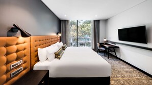 Une chambre d’hôtel moderne avec un grand lit, un bureau et une télévision.