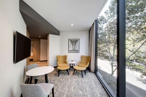 Una habitación moderna con dos sillones, una mesita redonda y un televisor de pantalla plana en la pared.