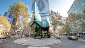 Un bâtiment moderne doté d’une façade en verre et d’une structure triangulaire distinctive à l’entrée.
