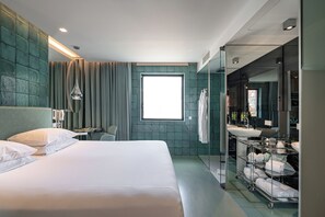 A modern hotel room with a large bed, a bathroom with a glass shower enclosure, and a view of the city. - WC by The Beautique Hotels (Lisbon)