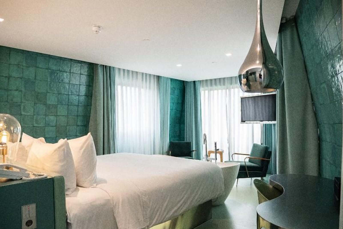 Une chambre d’hôtel avec un grand lit, un bureau et une chaise.