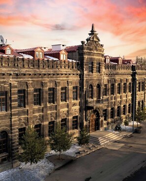 A historic building with a prominent clock tower, large windows, and a symmetrical facade. - Cheltikov Hotel (Kars)