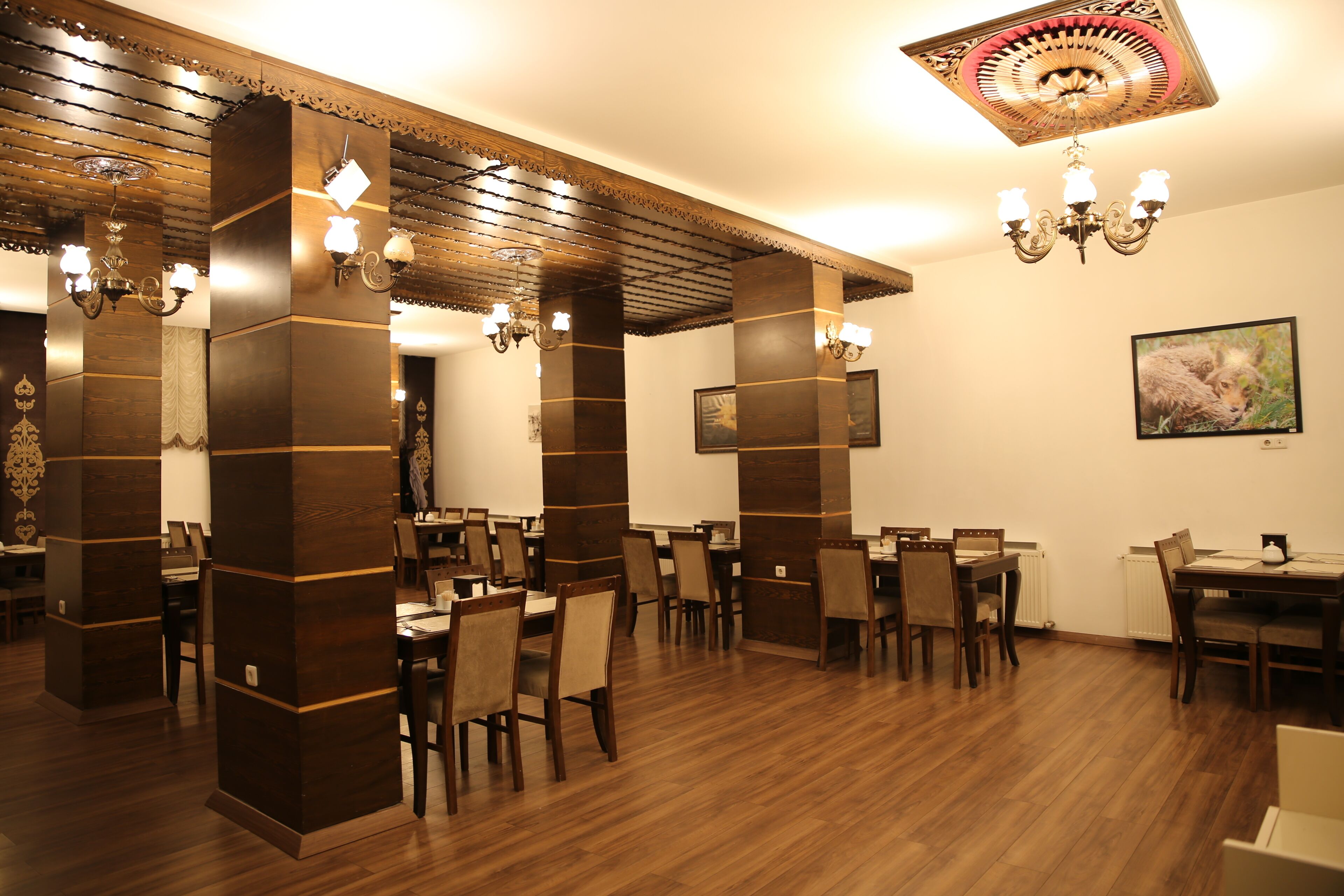 A restaurant with wooden paneling, chandeliers, and a framed picture on the wall.