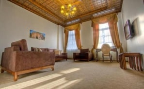 A living room with a sofa, armchairs, a small table, and a TV. - Cheltikov Hotel (Kars)