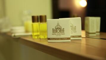 A hotel reception area with a wooden counter displaying a bottle of Makya Jamugyu / Cotton and a card with the hotel name HOTEL CHELTIKOV.