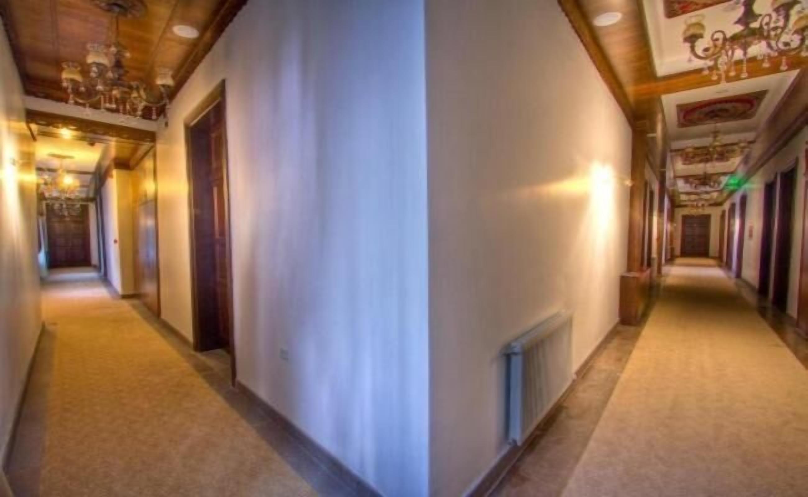 Un corridoio con pannelli in legno, un termosifone e un lampadario.