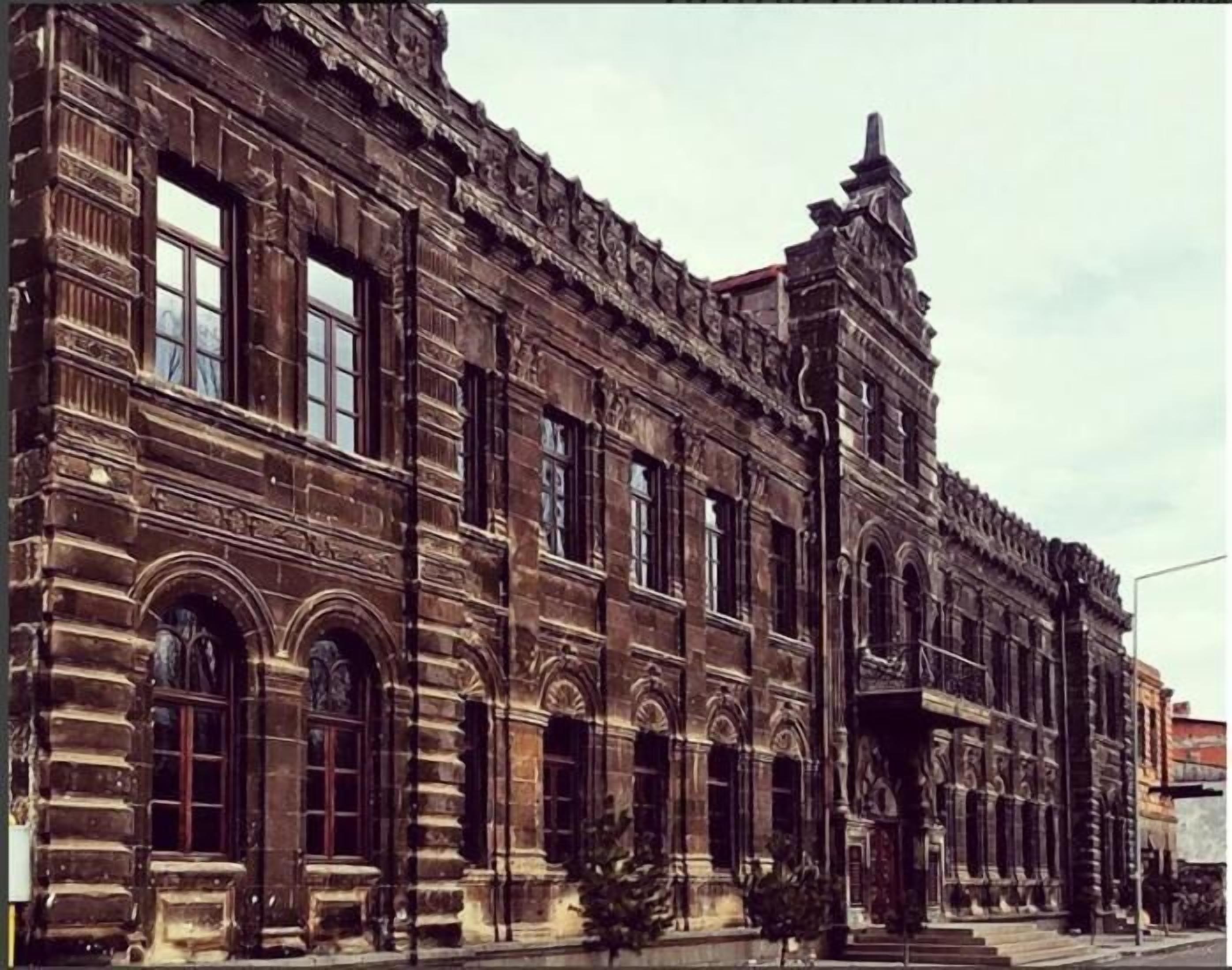 Un edificio grande e histórico con múltiples ventanas de arco y detallada ornamentación de piedra.