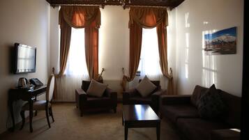 A living room with two sofas, a coffee table, a TV, and a desk with a lamp.