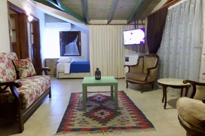 A living room with a sofa, armchairs, a small table, and a television.