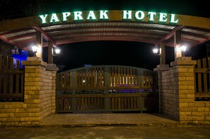 The entrance to Yaprak Hotel with a gated driveway and illuminated sign.