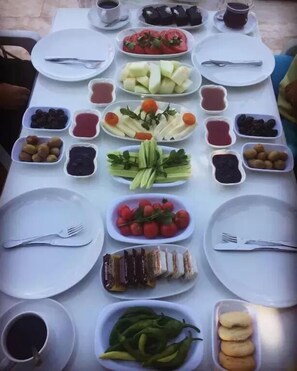 A table set with various dishes, including fruits, vegetables, and desserts, arranged for a meal.