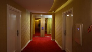 A hotel hallway with red carpet, white doors, and a security camera. - Bilgehan Hotel (Antalya)