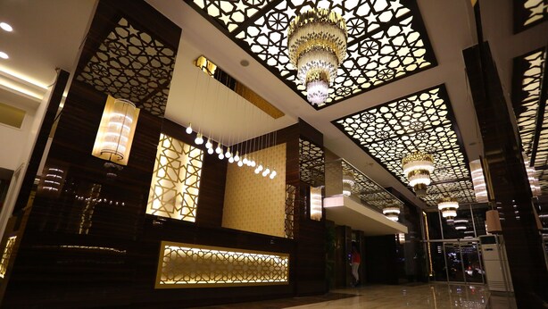 A lobby with a reception desk, chandeliers, patterned ceiling, and a polished floor. - Bilgehan Hotel (Antalya)