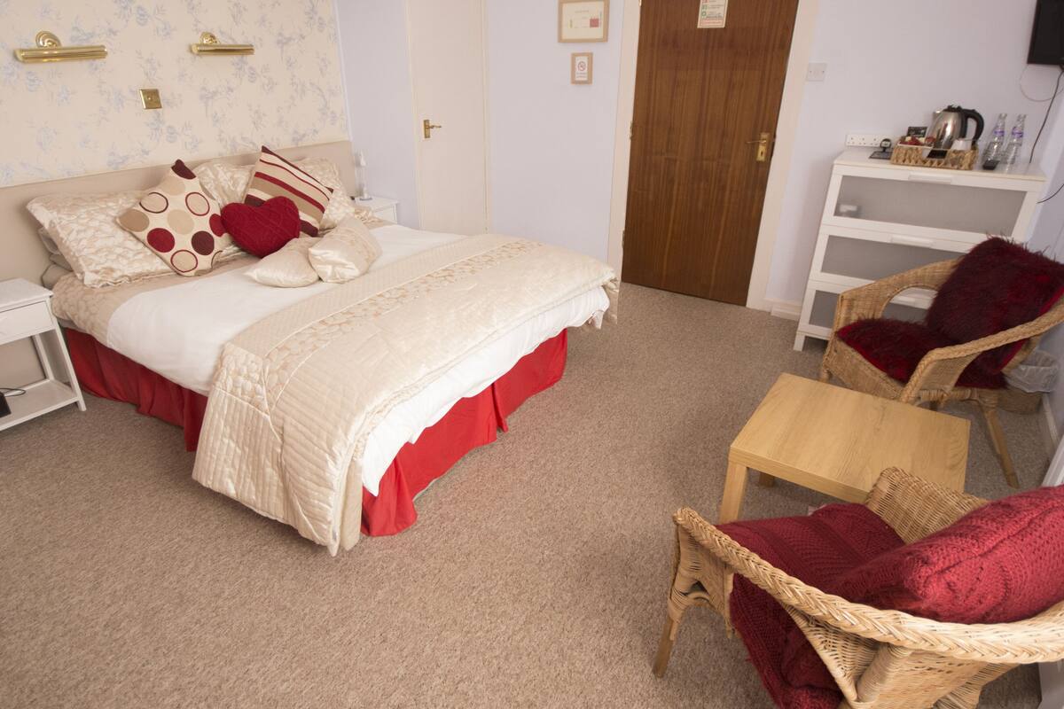 A bedroom with a bed, two chairs, a small table, and a nightstand.
