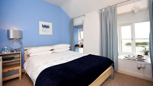 Un dormitorio con cama, mesita de noche, lámpara y ventana con cortinas.