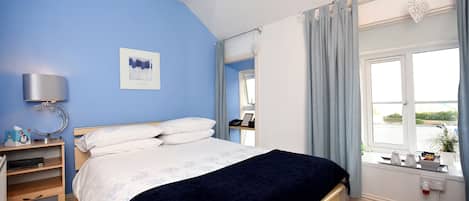A bedroom with a bed, bedside table, lamp, and a window with curtains.