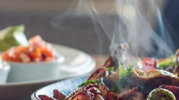 A plate of food with smoke rising from it, placed on a wooden board.