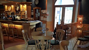 Un interior de restaurante con mobiliario de madera, una zona de bar y un ventanal grande.