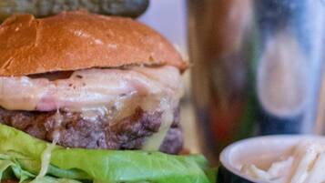Ein Burger mit Pommes und Gurke auf einem Holztisch.