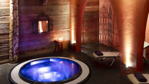 Een spa-ruimte met een jacuzzi, houten wanden en een decoratieve spiegel.