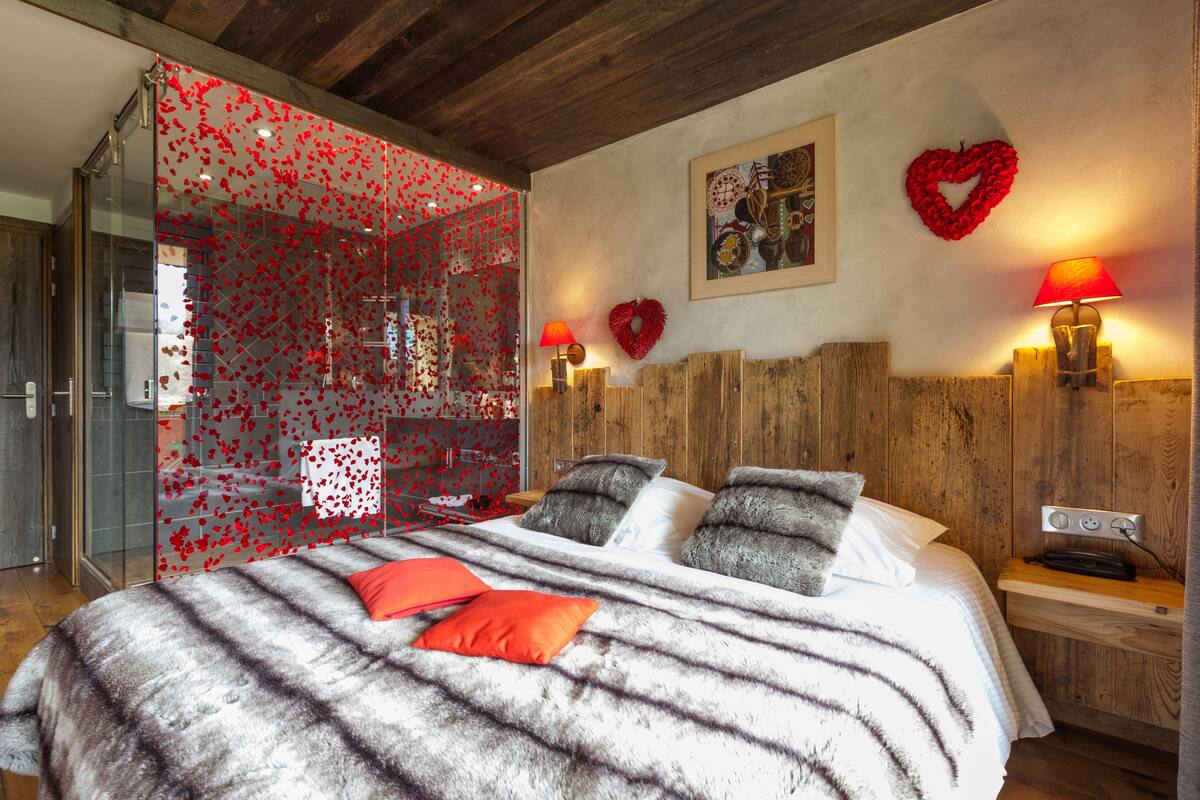 Un dormitorio con una cama grande, dos lámparas de noche, cabecera de madera y cabina de ducha de vidrio.
