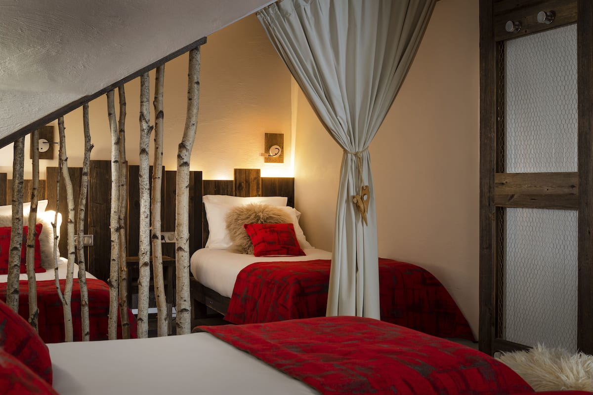 Un dormitorio con cama, mesita de noche, lámpara y ventana con cortinas.