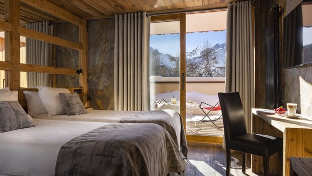 Een houten kamer met twee bedden, een eettafel en een stoel.